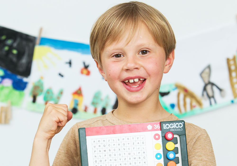 Lachendes Kind mit LOGICO-Rahmen PICCOLO im Klassenraum einer Grundschule